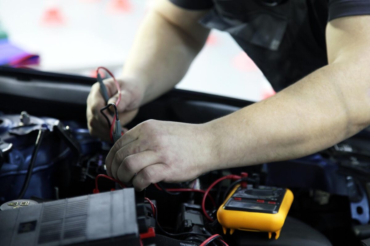 Male hands performing car repair with open hood